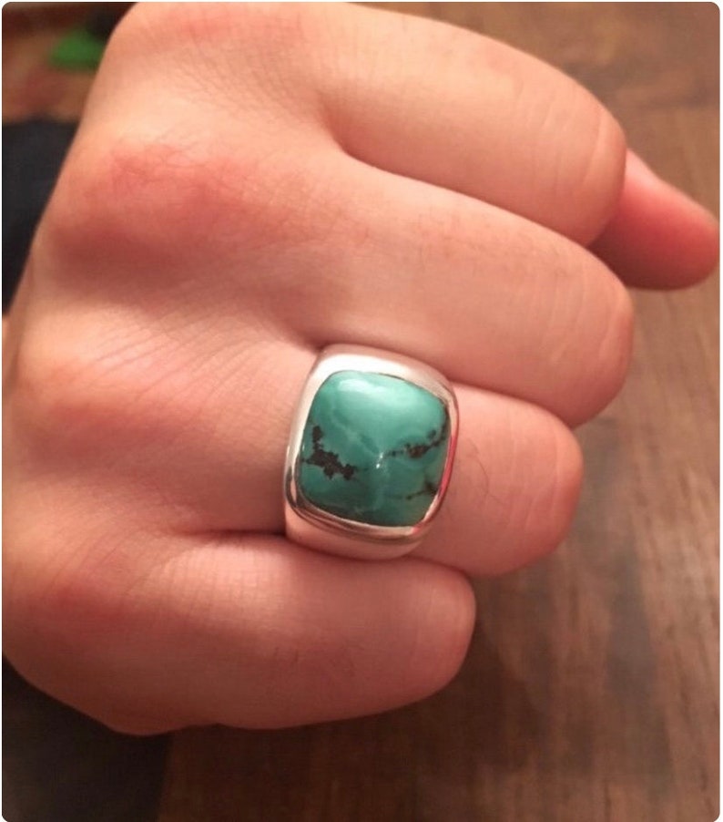 May include: A silver ring with a square turquoise stone set in a bezel setting.