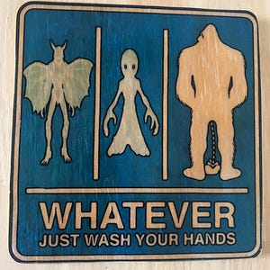 Puede incluir: Cartel de madera con fondo azul y tres figuras de dibujos animados: una criatura parecida a un murciélago, un extraterrestre y Bigfoot. El texto dice "WHATEVER JUST WASH YOUR HANDS".