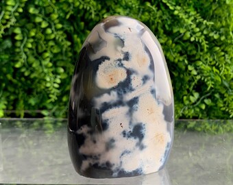 May include: A white and gray agate freeform with a smooth, polished surface. The agate has a unique pattern of white and gray swirls and spots.