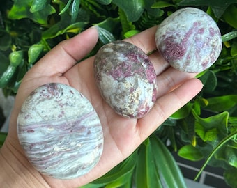 May include: Three smooth, polished stones with a swirling pattern of white, pink, and gray. The stones are tumbled and have a natural, organic look.