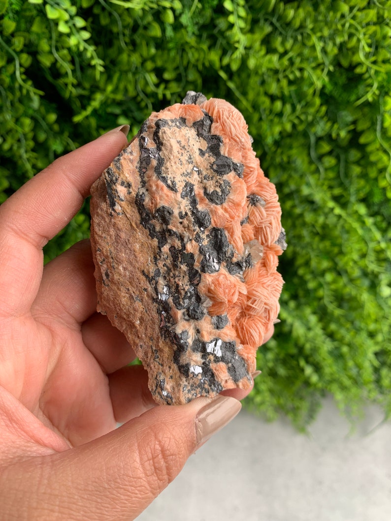 May include: A raw, pink and gray crystal cluster with a rough, natural texture. The crystal is a combination of pink and gray, with a rough, natural texture.