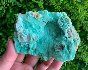 Puede incluir: Un gran cúmulo de cristales natural, rugoso, verde y marrón. El cristal tiene una superficie lisa y pulida y un exterior rugoso y texturizado.