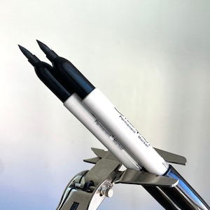 Puede incluir: Dos marcadores permanentes negros se mantienen unidos por una abrazadera de metal plateado. Los marcadores están etiquetados como "Permanent Marker".