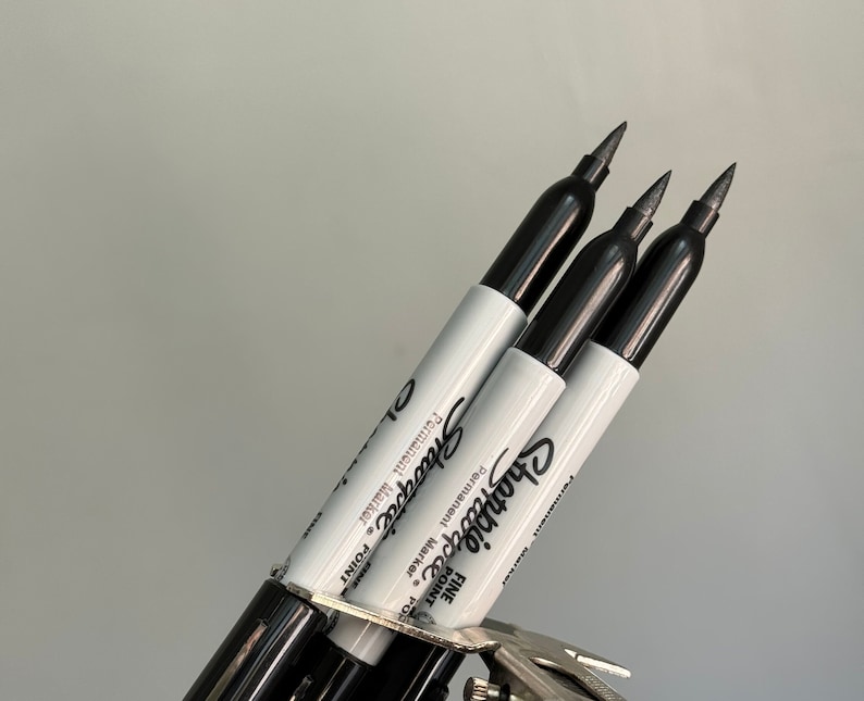 May include: Three black Sharpie fine point permanent markers with white labels.