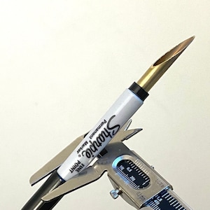 Könnte beinhalten: Eine silberne Schieblehre misst die Spitze eines goldenen Sharpie-Permanentmarkers mit einer feinen Spitze.