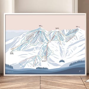 May include: A white framed print of a ski resort map with blue, red, and brown lines showing the ski runs. The map is set against a light pink background with a blue and white mountain range in the background.