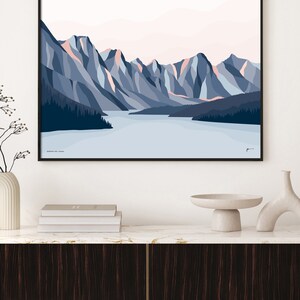 May include: A minimalist geometric illustration of a mountain range with a lake in the foreground. The mountains are shades of blue and pink, and the lake is a light blue. The text "Moraine Lake, Canada" is at the bottom of the image.