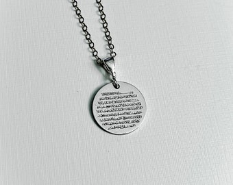 May include: A silver necklace with a round pendant featuring Arabic calligraphy. The pendant is about 1 inch in diameter.