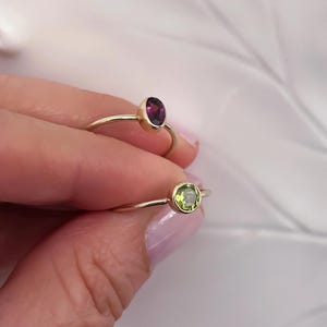 Pu&ograve; includere: Due anelli d'oro con pietre preziose. L'anello superiore ha una pietra ovale di colore viola. L'anello inferiore ha una pietra rotonda di colore verde.