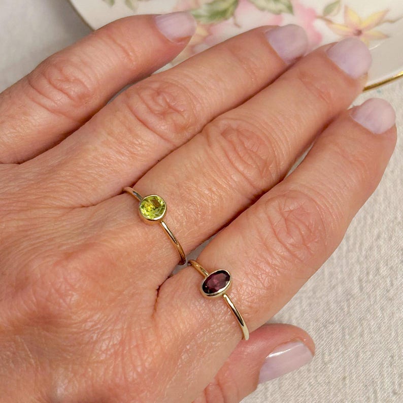 Pu&ograve; includere: Due anelli d'oro con pietre preziose. Un anello ha una pietra preziosa ovale verde, e l'altro anello ha una pietra preziosa ovale viola.