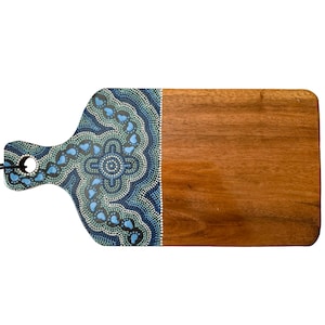 May include: A rectangular wooden serving board with a handle featuring a hole. One side of the board is decorated with a detailed dot art pattern in shades of dark blue, light blue, and white, while the other side shows the natural brown wood grain.
