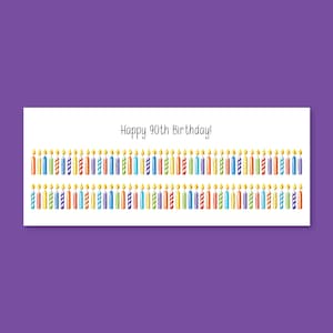 May include: A white rectangular card with the text "Happy 90th Birthday!" above two rows of colorful birthday candles. The candles have yellow flames and are in various colors, including red, blue, green, and yellow.