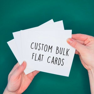 May include: A stack of white blank cards with the text "CUSTOM BULK FLAT CARDS" written in black marker.