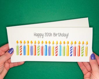 May include: A white card with the text "Happy 20th Birthday!" and a row of 20 colorful birthday candles with flames.
