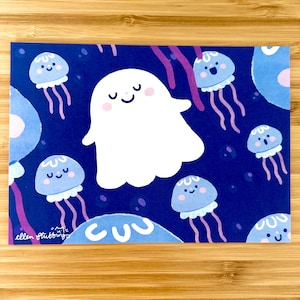 Könnte beinhalten: Ein fantasievoller Kunstdruck mit einem dunkelblauen Hintergrund, der ein lächelndes weißes Gespenst und hellblaue Quallen mit lächelnden Gesichtern zeigt. Die Signatur des Künstlers, "ellen stubbings", ist enthalten.