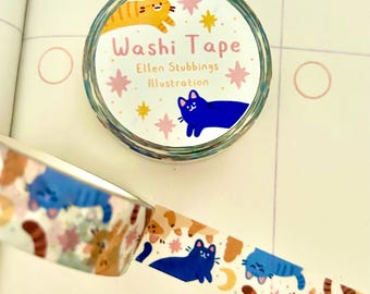 May include: Washi tape roll with a circular label featuring the text "Washi Tape Ellen Stubbins Illustration". The tape design includes illustrations of cats, stars, and moons in shades of blue, orange, and brown. The tape is unrolled, revealing more of the pattern.