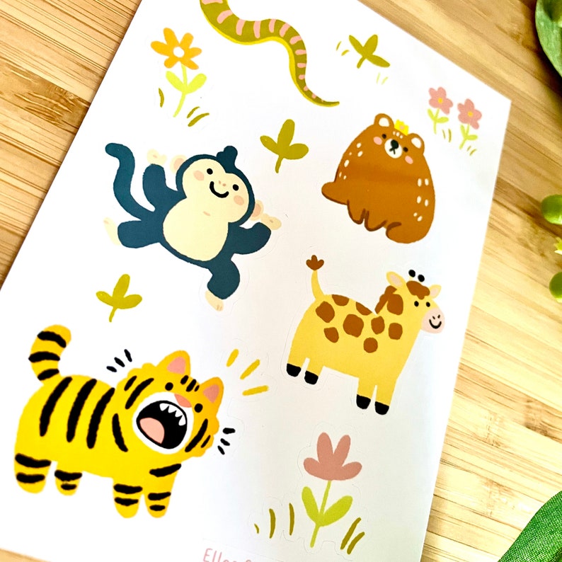 Op de afbeelding: Een vel met kleurrijke dieren stickers met een tijger, aap, giraffe, beer en slang. De stickers zijn perfect om een ​​toets van whimsy toe te voegen aan dagboeken, planners of elk ander creatief project.