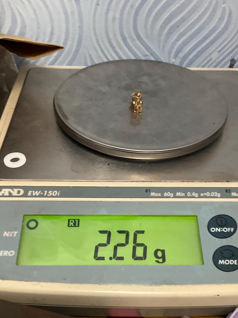K&ouml;nnte beinhalten: Ein kleiner goldfarbener Anh&auml;nger liegt auf der runden Plattform einer digitalen Waage. Das Display der Waage zeigt ein Gewicht von 2,26 Gramm an. Der Anh&auml;nger hat eine metallische Oberfl&auml;che und ein kompaktes, filigranes Design.