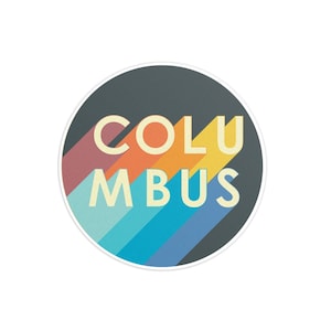 May include: A round sticker with a retro design featuring the word "COLUMBUS" in a yellow font on a dark gray background. The word is layered over a series of colorful stripes in shades of red, orange, yellow, blue, and green.