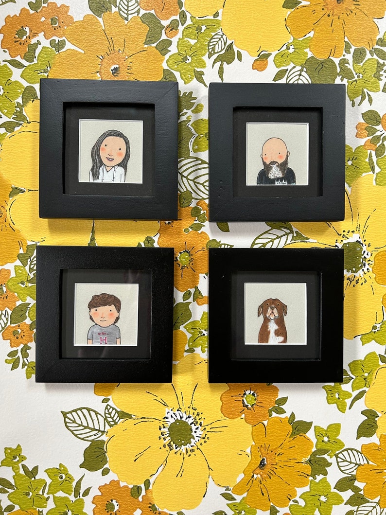 May include: Four black picture frames with white mats, each containing a hand-drawn illustration. The top left frame shows a woman with short brown hair, the top right frame shows a man with a beard, the bottom left frame shows a person with short brown hair, and the bottom right frame shows a brown and white dog.
