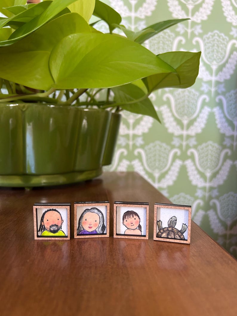 May include: Four small, square framed illustrations. The illustrations depict a person with a beard, a person with gray hair, a person with brown hair, and a turtle. The frames are made of wood.