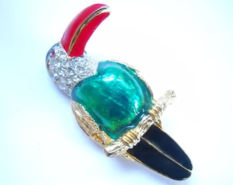 May include: A gold-tone toucan brooch with red beak, green body, black tail, and clear rhinestone accents.