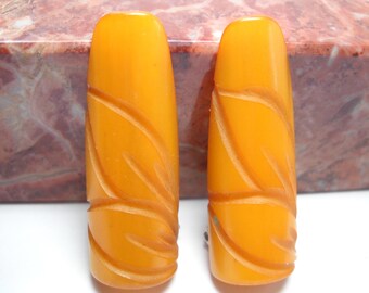 May include: A pair of yellow carved plastic earrings with a leaf design.