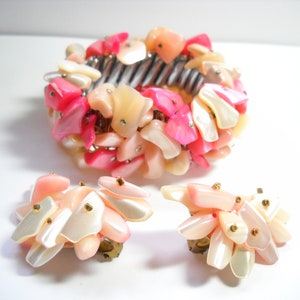 K&ouml;nnte beinhalten: Ein Set aus rosa und wei&szlig;en Muschel-Schmuck, bestehend aus einem Armband und einem Paar Ohrringen. Das Armband besteht aus vielen kleinen, unregelm&auml;&szlig;ig geformten Muscheln, und die Ohrringe sind im Design &auml;hnlich.