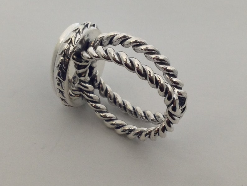 May include: Silver ring with a twisted rope design. The ring is made of two bands of twisted metal that are intertwined.