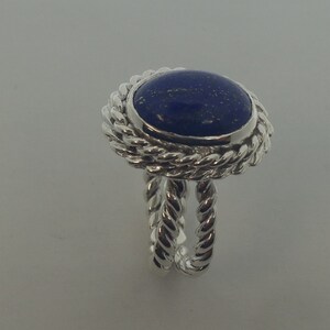 Puede incluir: Un anillo de plata con una piedra de lapisl&aacute;zuli azul engastada en un dise&ntilde;o de cuerda.