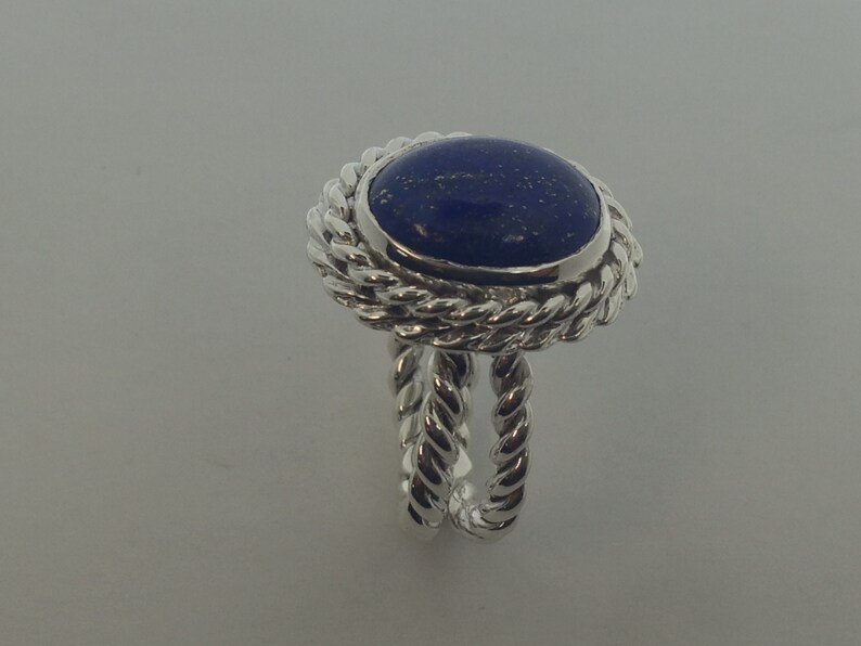 Puede incluir: Un anillo de plata con una piedra de lapisl&aacute;zuli azul engastada en un dise&ntilde;o de cuerda.