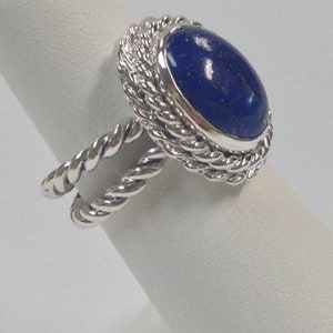Puede incluir: Un anillo de plata con una piedra preciosa de lapisl&aacute;zuli azul engastada en un dise&ntilde;o de cuerda trenzada.