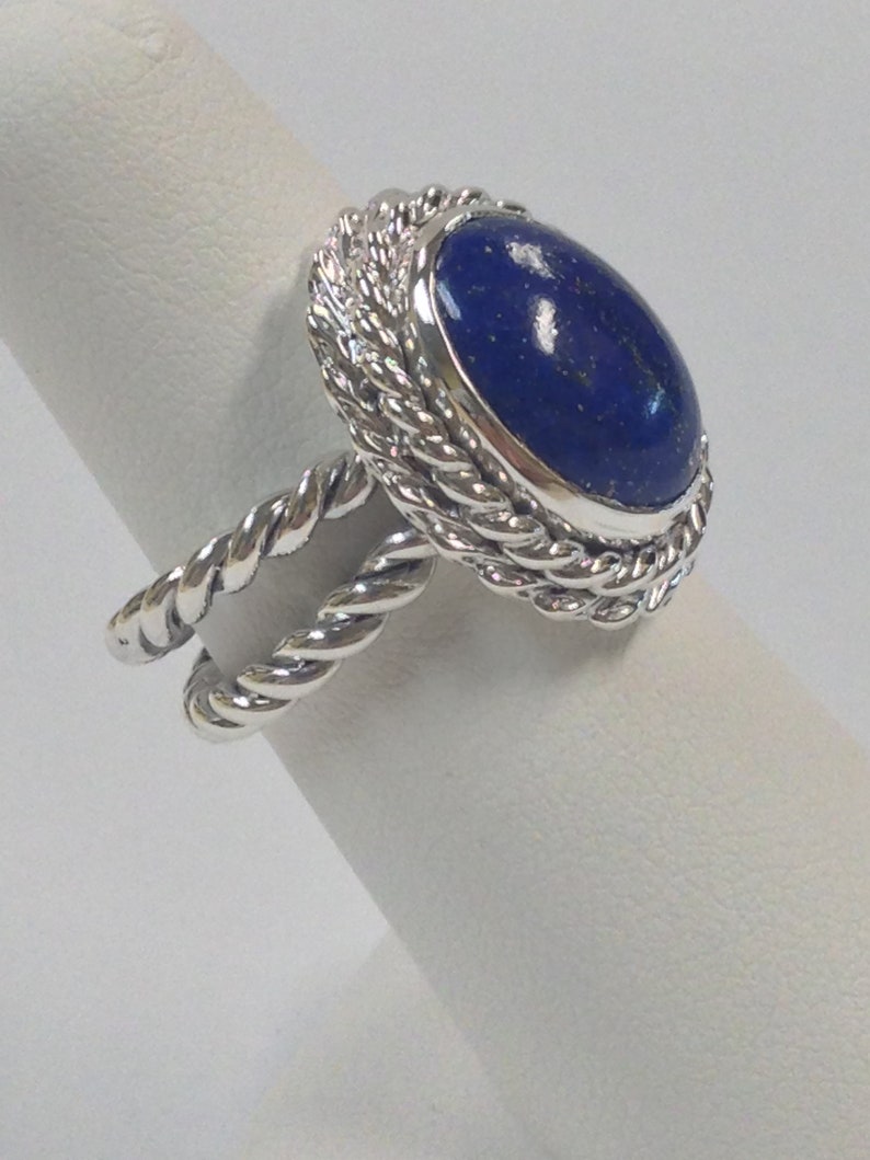 Puede incluir: Un anillo de plata con una piedra preciosa de lapisl&aacute;zuli azul engastada en un dise&ntilde;o de cuerda trenzada.