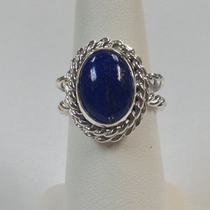 Puede incluir: Un anillo de plata con una piedra de lapisl&aacute;zuli azul engastada en un dise&ntilde;o de cuerda.