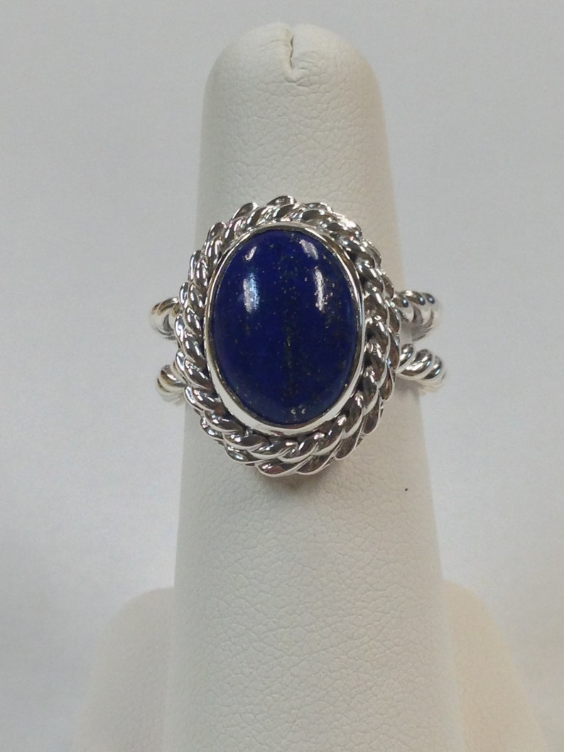Puede incluir: Un anillo de plata con una piedra de lapisl&aacute;zuli azul engastada en un dise&ntilde;o de cuerda.