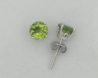 May include: A pair of silver earrings with green gemstones. The earrings have a round shape and a simple design.