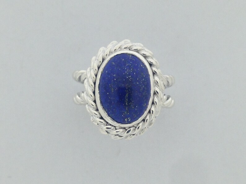 Puede incluir: Un anillo de plata con una piedra de lapisl&aacute;zuli azul engastada en un dise&ntilde;o de cuerda.