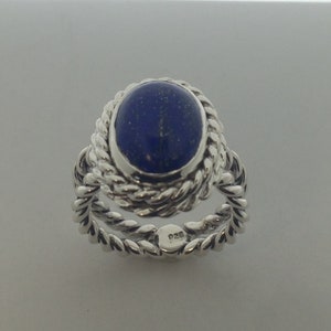 Puede incluir: Un anillo de plata con una piedra de lapisl&aacute;zuli azul engastada en un dise&ntilde;o de cuerda. El anillo est&aacute; marcado con "925" en la banda interior.