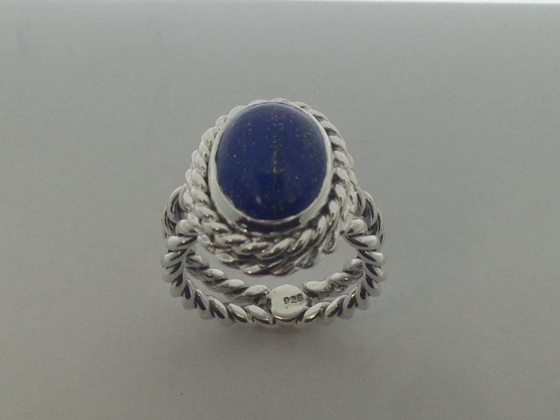 Puede incluir: Un anillo de plata con una piedra de lapisl&aacute;zuli azul engastada en un dise&ntilde;o de cuerda. El anillo est&aacute; marcado con "925" en la banda interior.