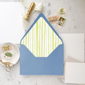 May include: A blue envelope with a white and green striped liner. The liner has a watercolour effect.