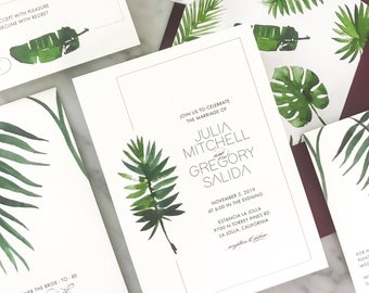 May include: A white wedding invitation with green tropical leaves and the text "Join us to celebrate the marriage of Julia Mitchell and Gregory Salida" with the date and location of the wedding.