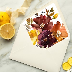 May include: A white envelope with a floral design on the flap. The design features watercolour flowers in shades of burgundy, orange, and yellow.