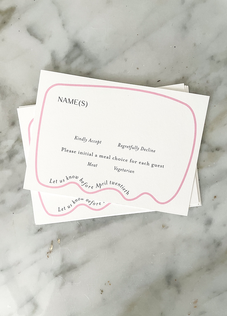 May include: A white RSVP card with pink borders. The card has a section for names, a section for meal choices, and a section for a deadline. The text on the card reads: "NAME(S)", "Kindly Accept", "Regretfully Decline", "Please initial a meal choice for each guest", "Meat", "Vegetarian", "Let us know before April twentieth", "Let us know oefore."