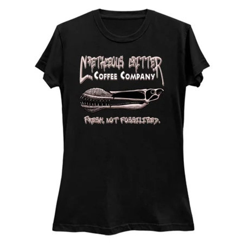 Puede incluir: Camiseta negra para mujer con un estampado gr&aacute;fico blanco de un logotipo de una empresa de caf&eacute;. El logotipo dice "N'R'THEOUS GRITTER COFFEE COMPANY" y presenta una imagen estilizada de un grano de caf&eacute;. El texto debajo del logotipo dice "FRESH, NOT FOSSILIZED."