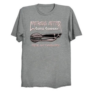Puede incluir: Una camiseta gris jaspeada con un gr&aacute;fico rosa de un molinillo de caf&eacute; con el texto "NRETHEOUS GRINDER COFFEE COMPANY" y "FRESH, NOT FORBIDDEN."