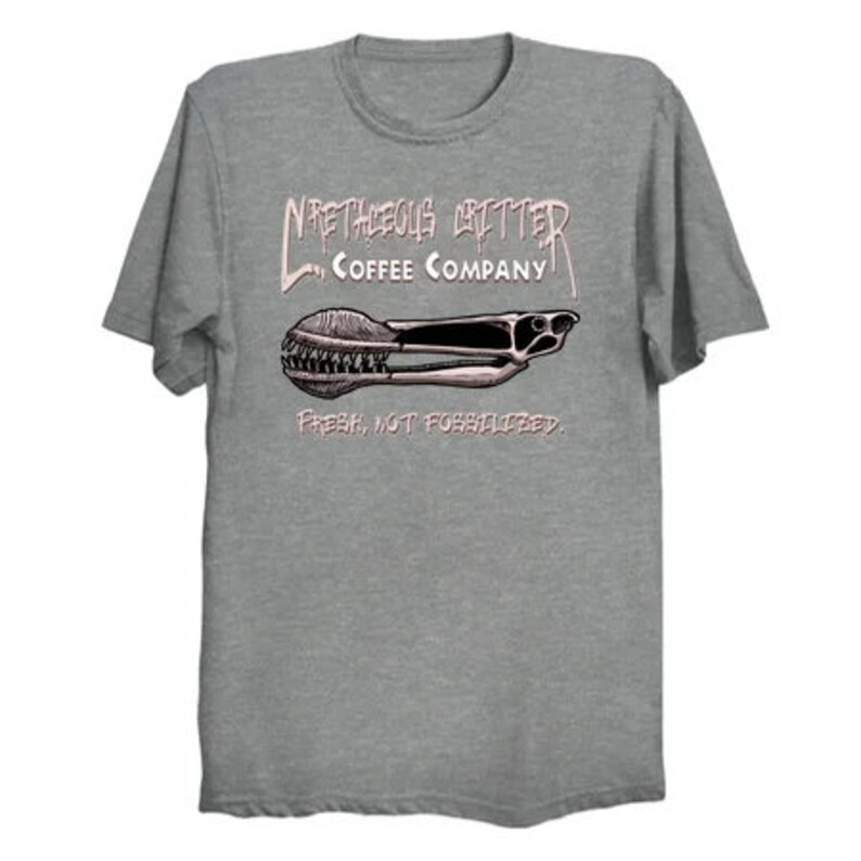 Puede incluir: Una camiseta gris jaspeada con un gr&aacute;fico rosa de un molinillo de caf&eacute; con el texto "NRETHEOUS GRINDER COFFEE COMPANY" y "FRESH, NOT FORBIDDEN."