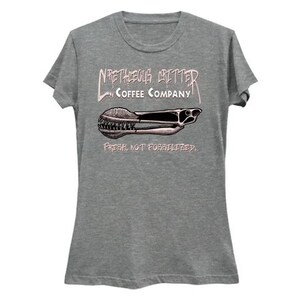 Puede incluir: Una camiseta gris jaspeada para mujer con un gr&aacute;fico de un molinillo de caf&eacute; y el texto "N'RTHEGUS GRITTER COFFEE COMPANY. FRESH, NOT FOSSILIZED."