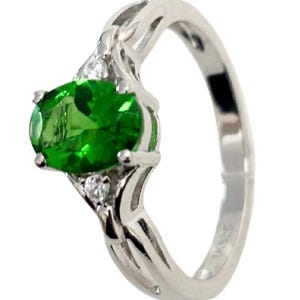 May include: A silver ring with a large green oval gemstone and smaller clear gemstones on the band.
