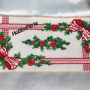 May include: A white beaded Christmas table runner with red and green holly and bow designs. The runner has a gold beaded border and the text "HobbyPerle" is embroidered in the center.