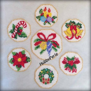 May include: Seven beaded Christmas ornaments with various designs, including a wreath, a poinsettia, a candy cane, and a bow with bells. The ornaments are white with gold trim and are arranged in a circle on a white background. The text "HobbyPerle" is visible in the center of the image.